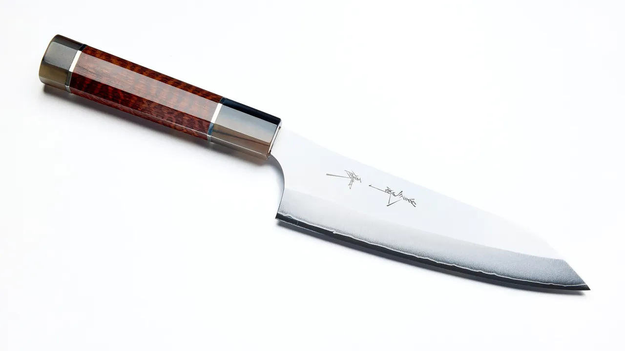 Faca japonesa de cozinha do tipo bunka sobre fundo branco, com cabo octogonal de madeira avermelhada e virola escura, a lâmina de aço polido com inscrição gravada em japonês.