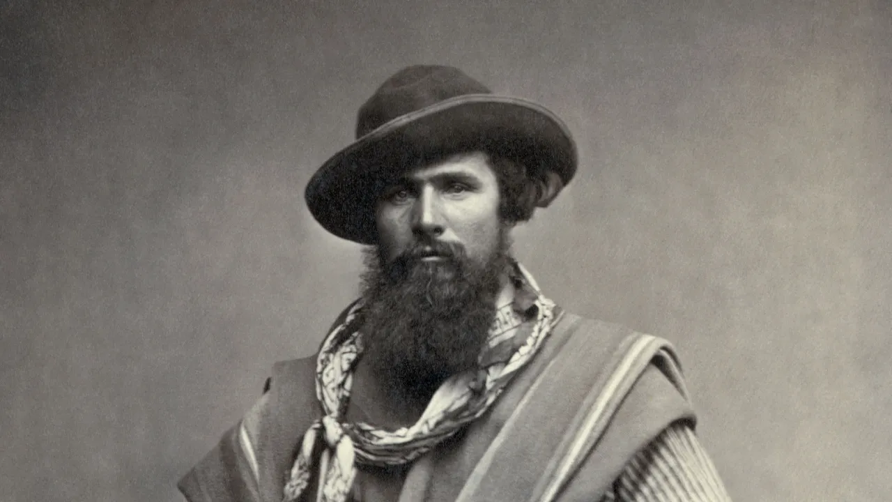 Retrato de estúdio de um gaúcho barbado de 1868, com chapéu, poncho e chiripá, tirador com rastra de moedas de prata na cintura e o cabo de um facão à mostra.