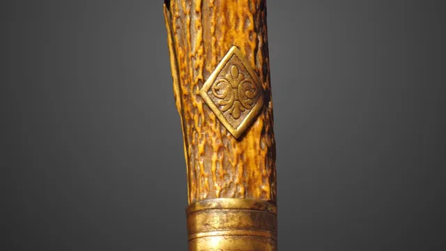 Empunhadura de uma faca de caça alemã do século XIX sobre fundo escuro: pomo de bronze em forma de cabeça de javali, cabo de chifre de veado com medalhão em losango, guarda cruzada de bronze lavrado e o início da lâmina larga.