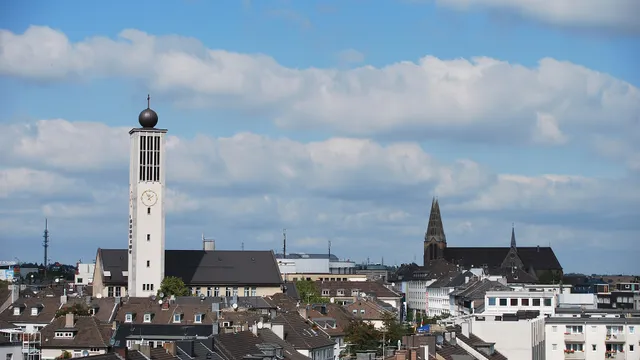 Vista dos telhados do centro de Solingen, na Alemanha, com a torre de relógio da igreja em primeiro plano e torres de igrejas antigas ao fundo.