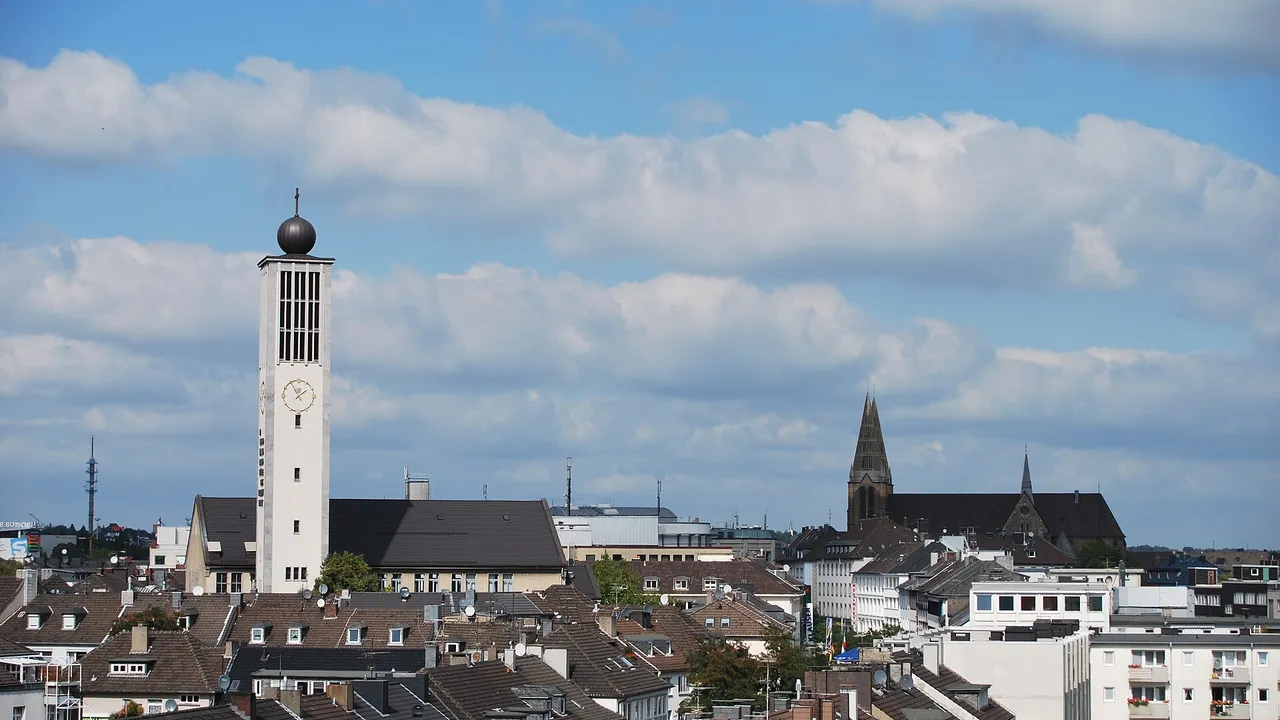 Vista dos telhados do centro de Solingen, na Alemanha, com a torre de relógio da igreja em primeiro plano e torres de igrejas antigas ao fundo.